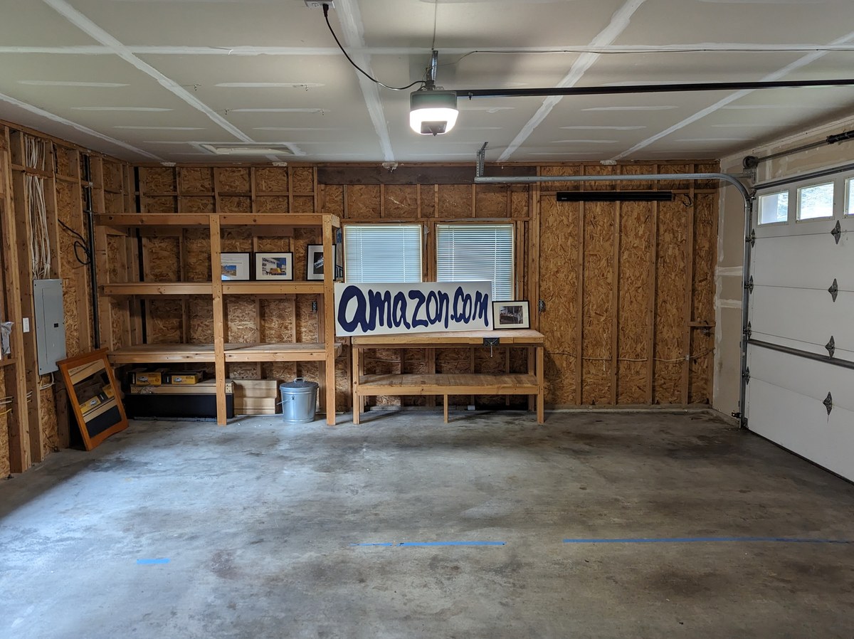 Photo: the inside of an empty garage with a hand-painted amazon.com sign on a workbench.