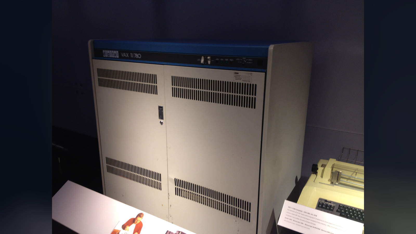 Photo: a cream-colored DEC VAX-11/780 minicomputer cabinet with a blue top panel and the model name on the front, on display in a dim museum gallery.
